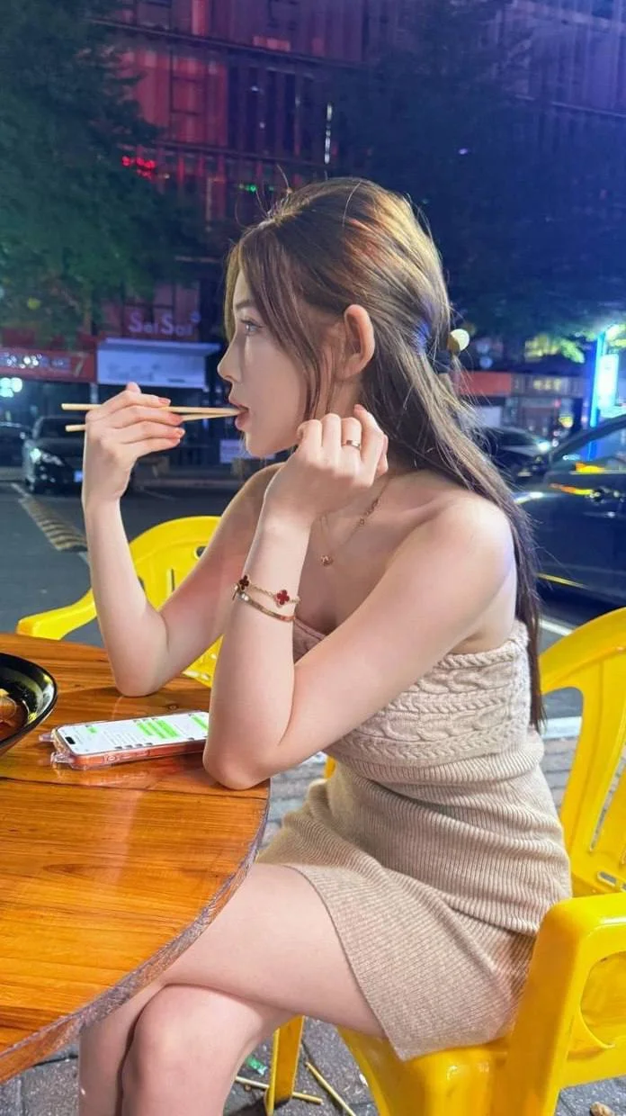 御姐侧坐街边吃东西