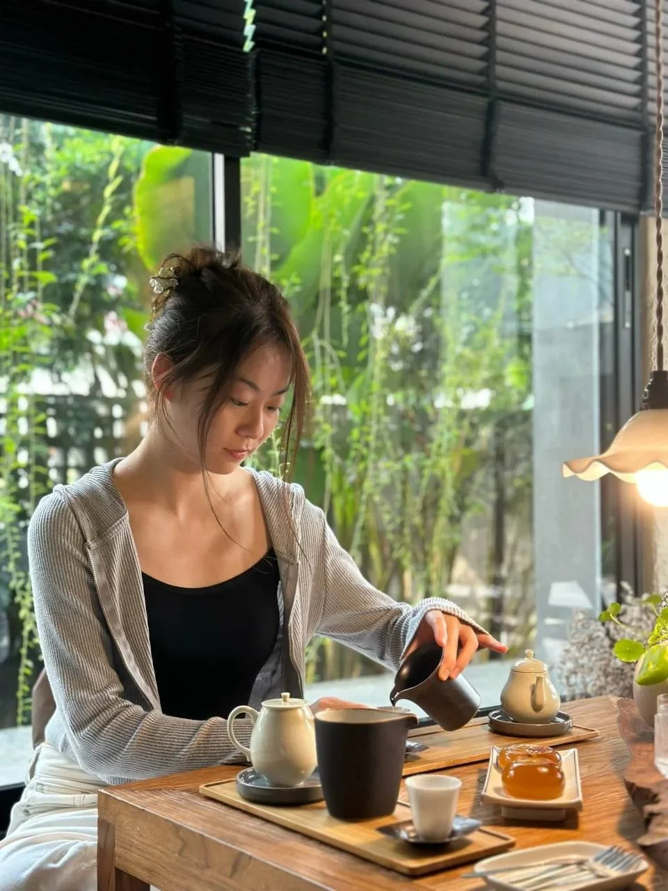 女子低头倒茶入黑杯