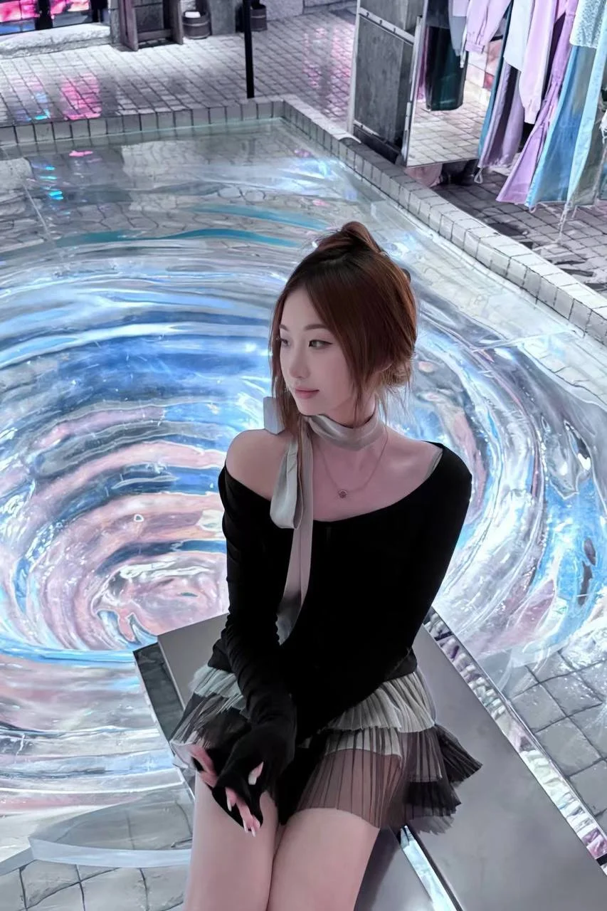 女孩坐在彩色水波纹地面边，黑手套和丝巾