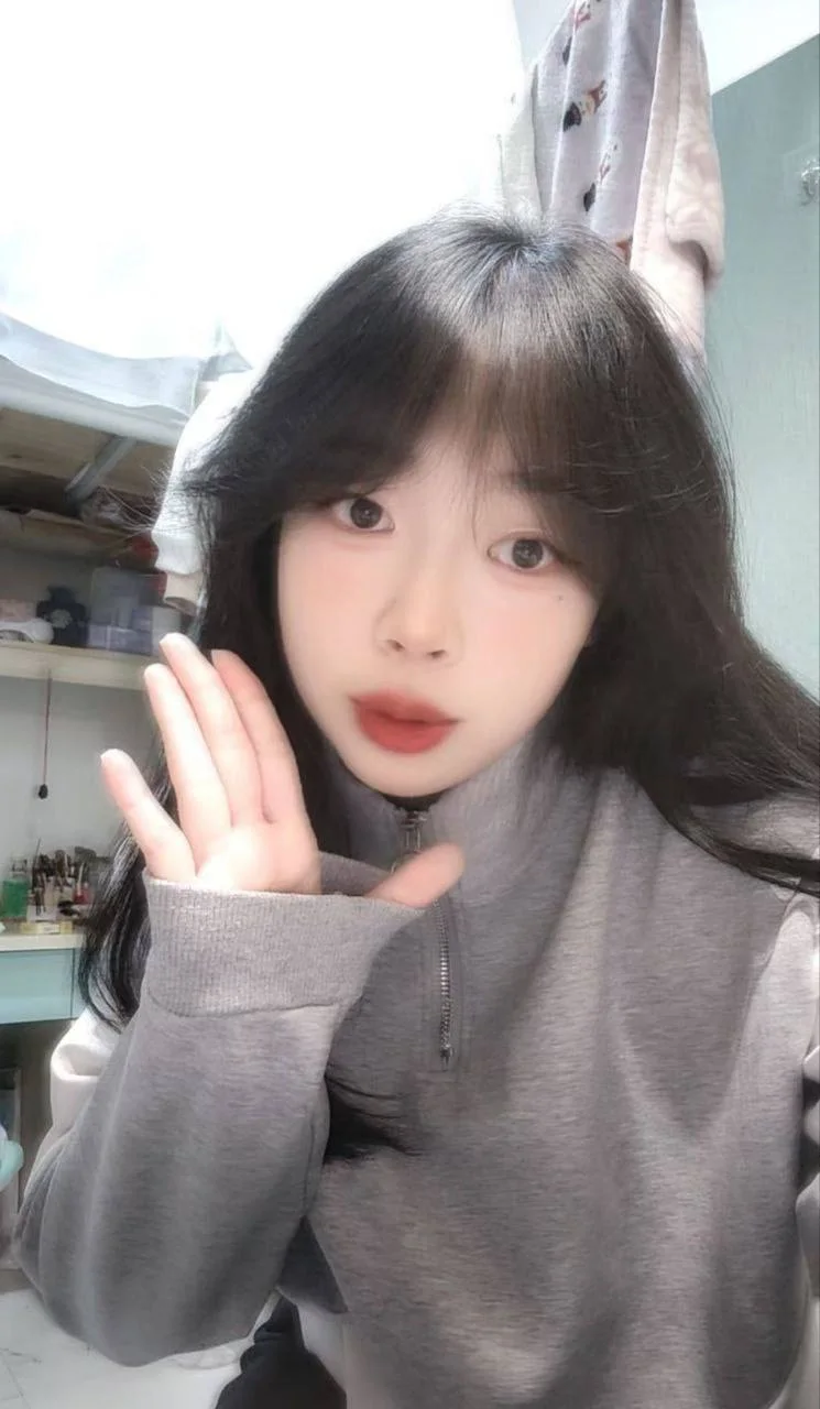 黑发女孩抬手比心对着镜头