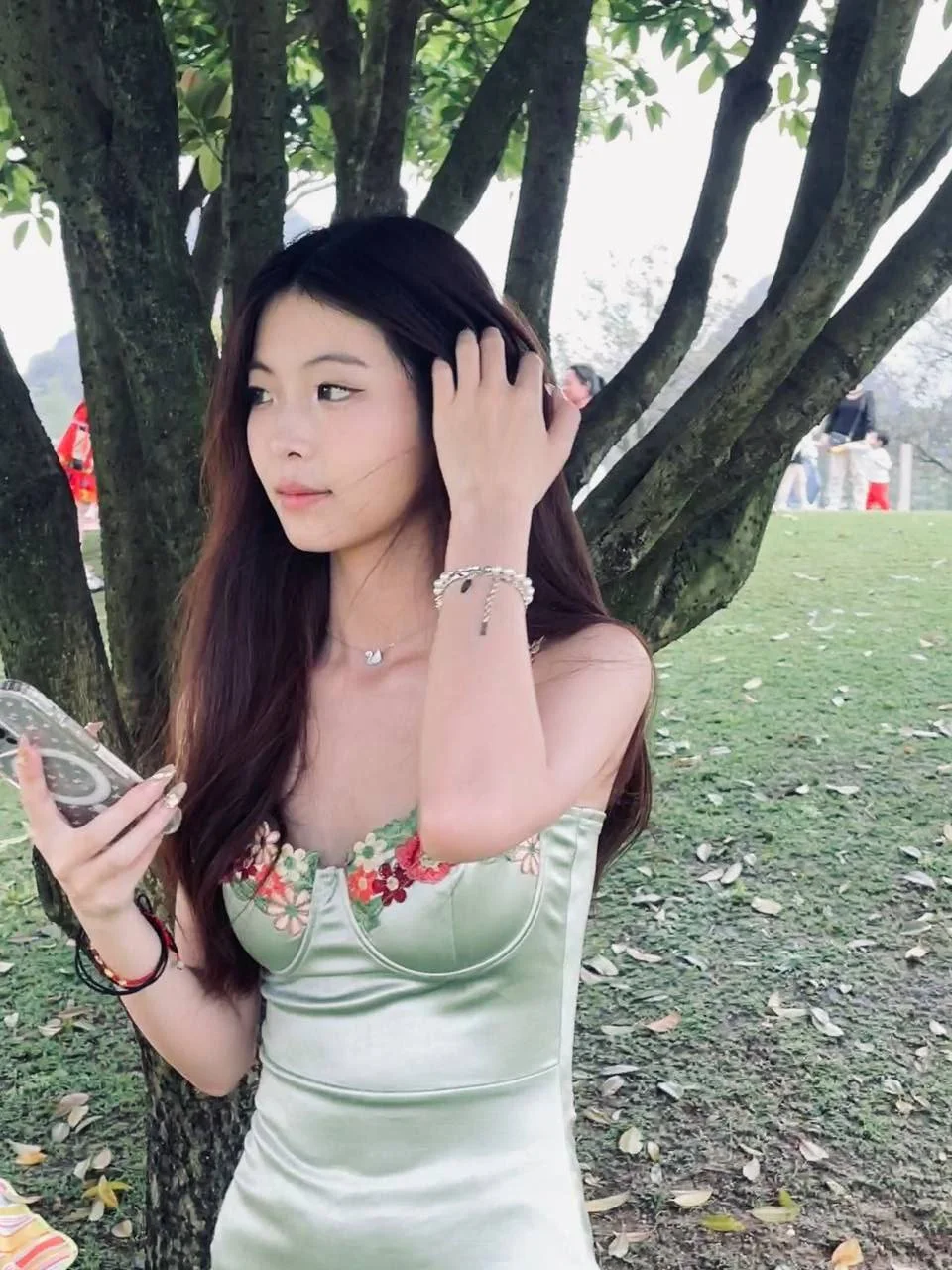 康若男靠树干手拿手机