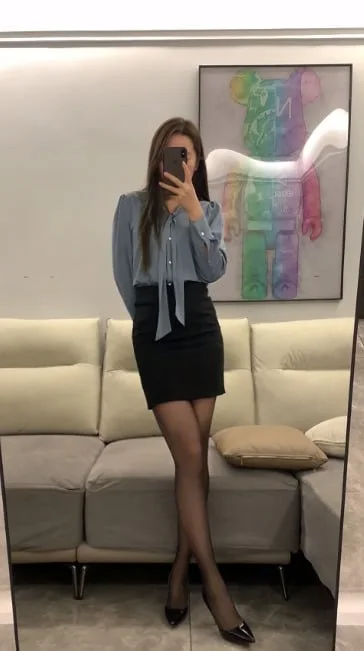 蓝衬衫黑裙女子站在沙发前举手机自拍