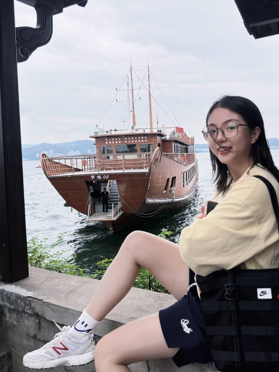 女生坐在湖边石栏上望向镜头