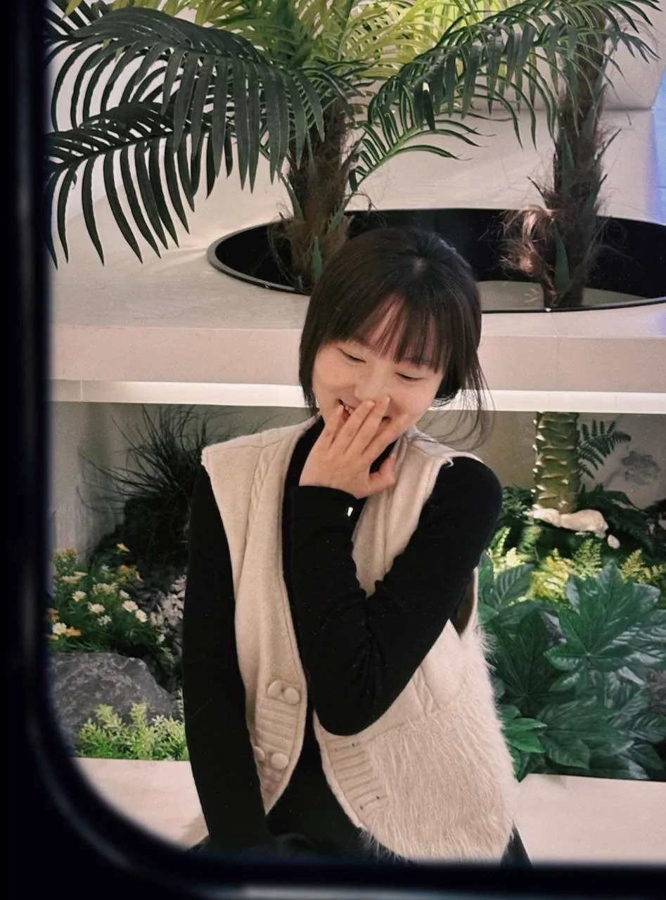 女孩捂嘴笑，身后绿植层层