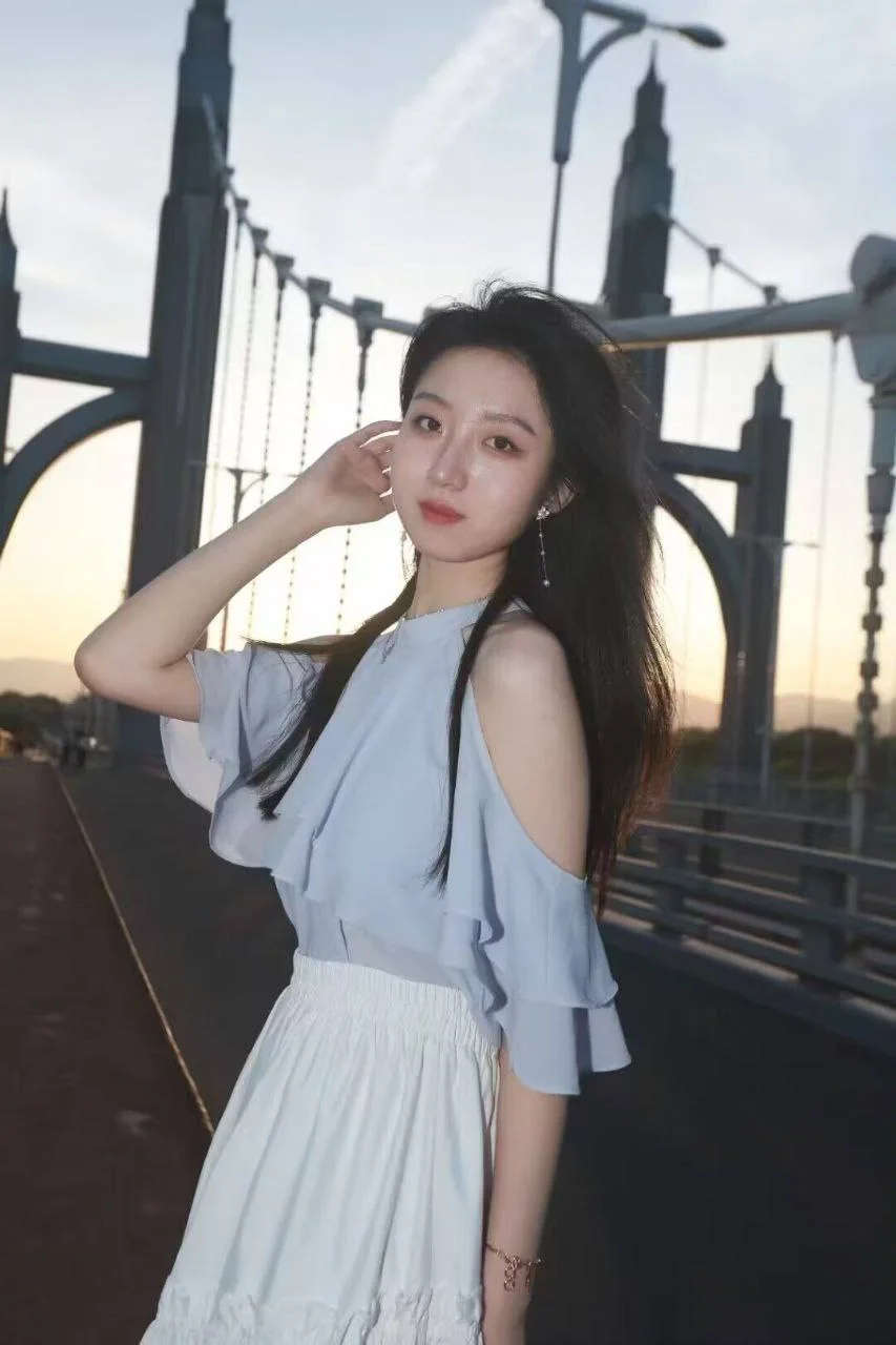 长发女子手扶额头站在大桥上