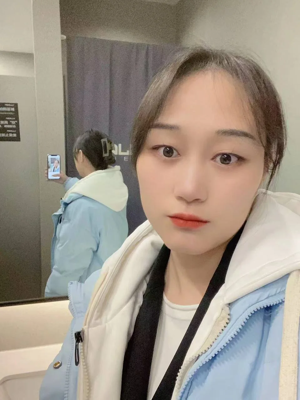 蓝白外套女孩自拍，身后镜子里反射出背影