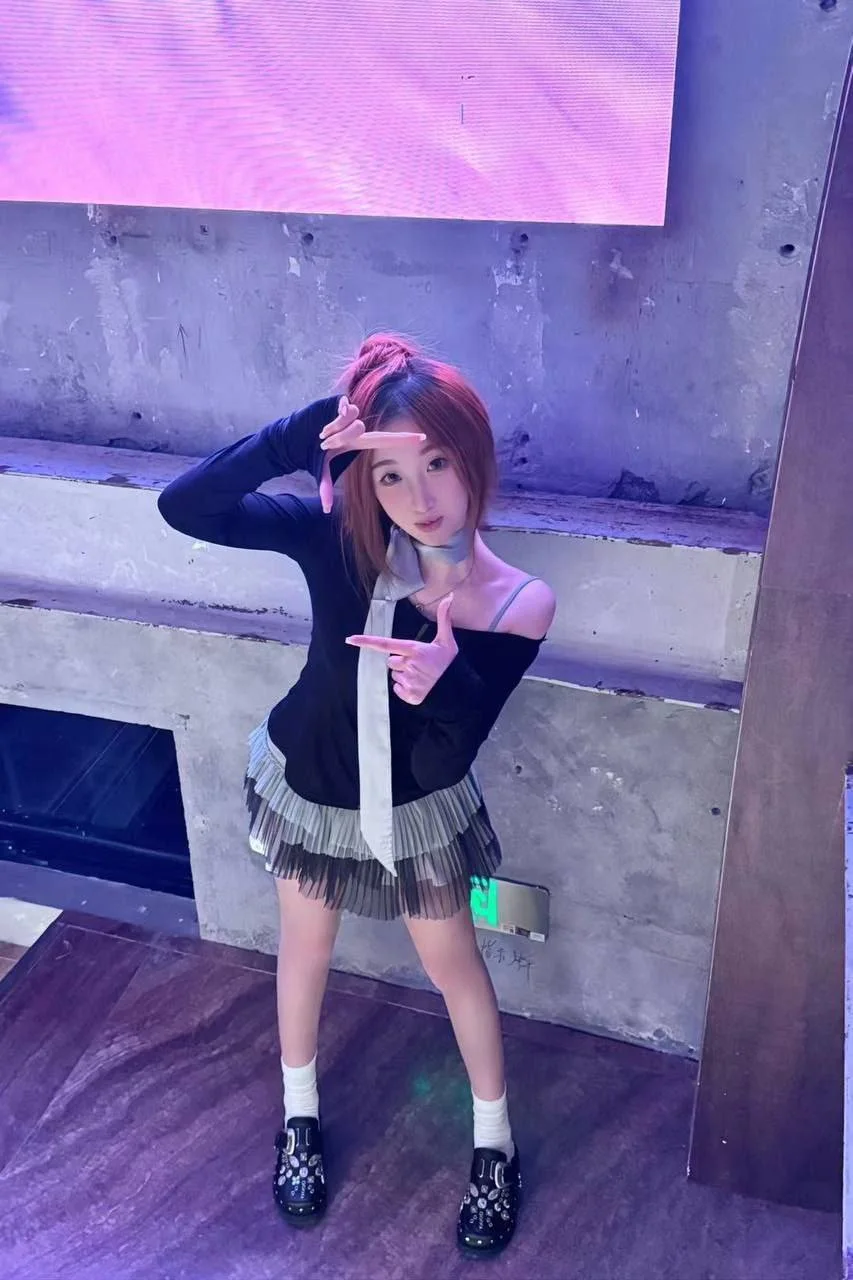 女孩比剪刀手pose，身后水泥墙和大屏