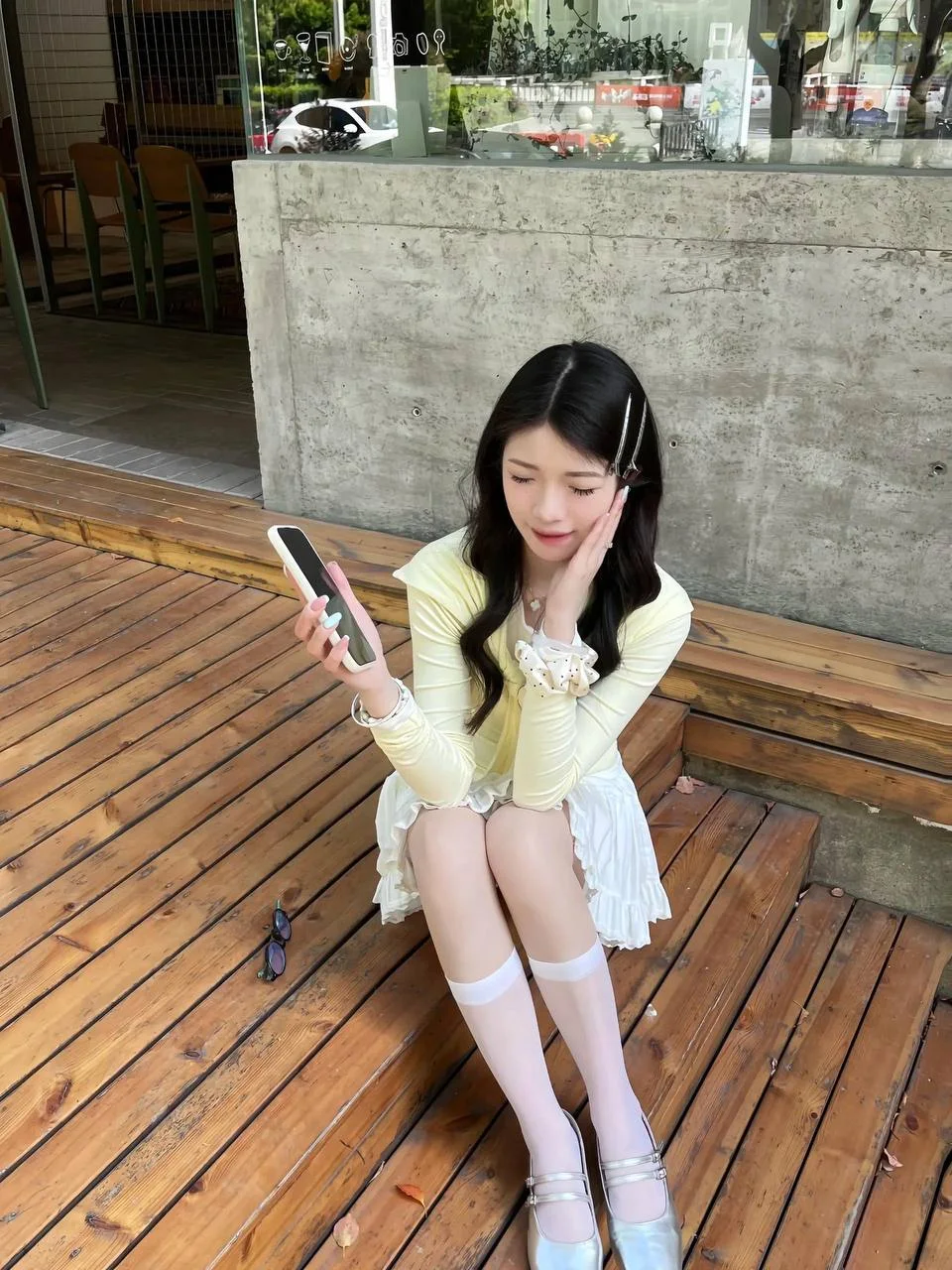 女生坐在木台阶上看手机