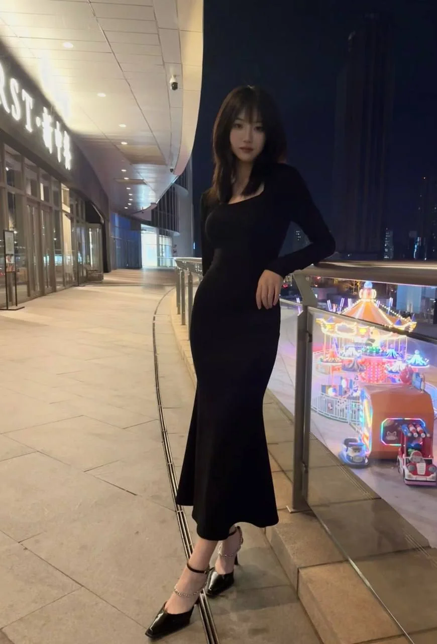黑长裙女子靠栏杆站立
