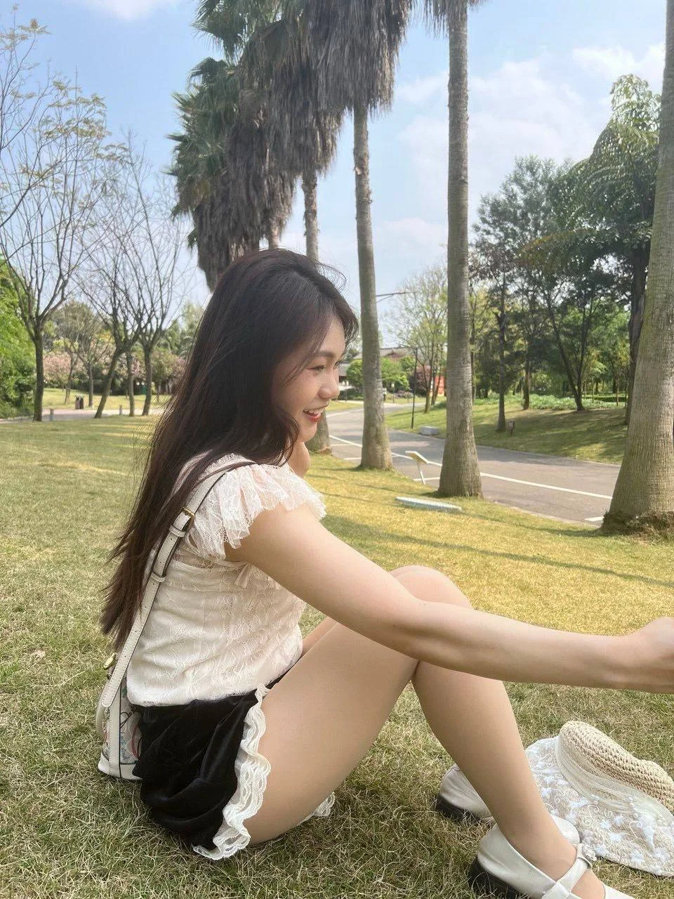 草坪上侧坐的长发女子伸臂自拍