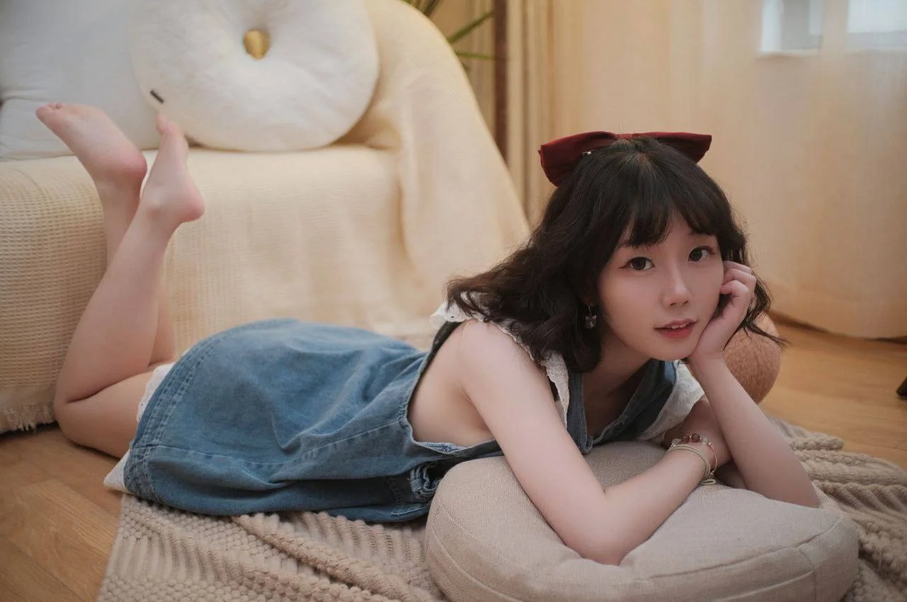 牛仔裙红蝴蝶结趴在抱枕上