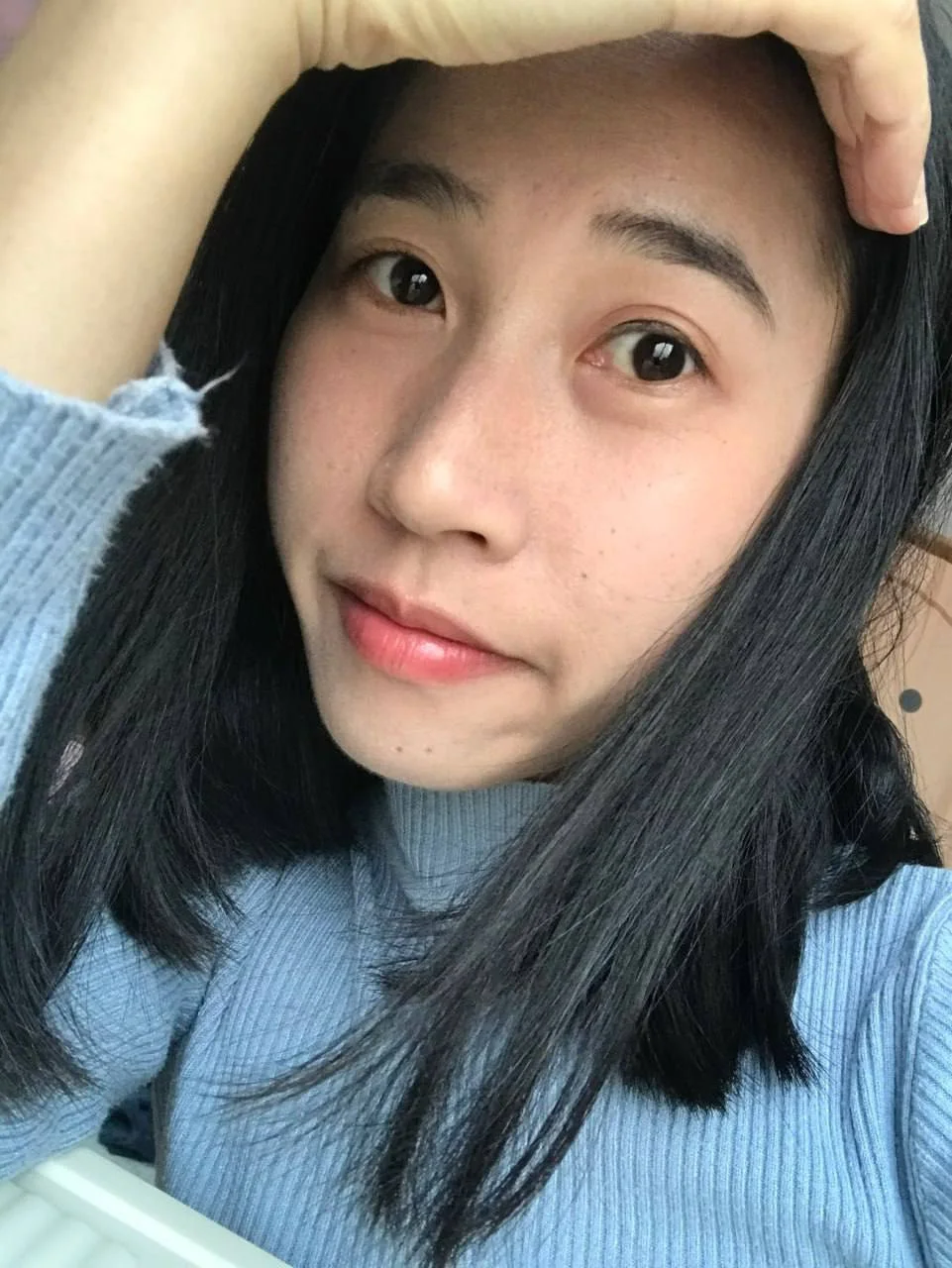 蓝毛衣女孩手遮额头