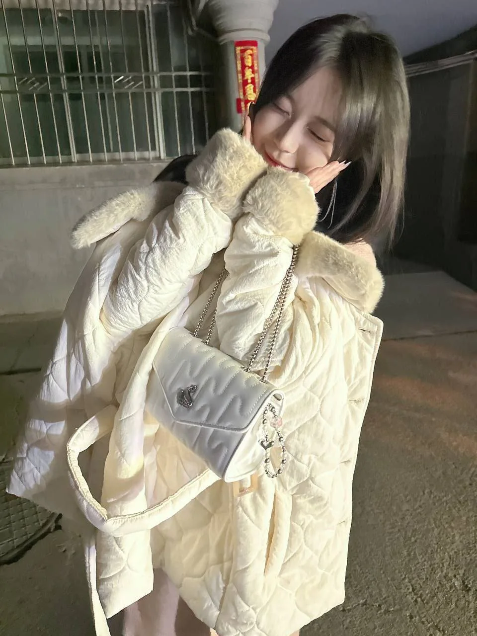 女孩双手捧脸微笑，白色羽绒服挎白色链条包