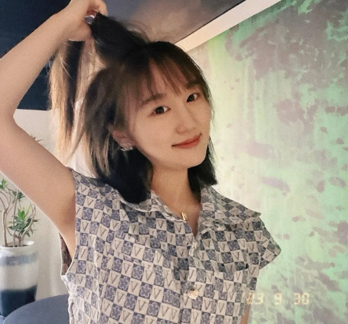 女孩抬手扎高马尾，墙上色块斑驳