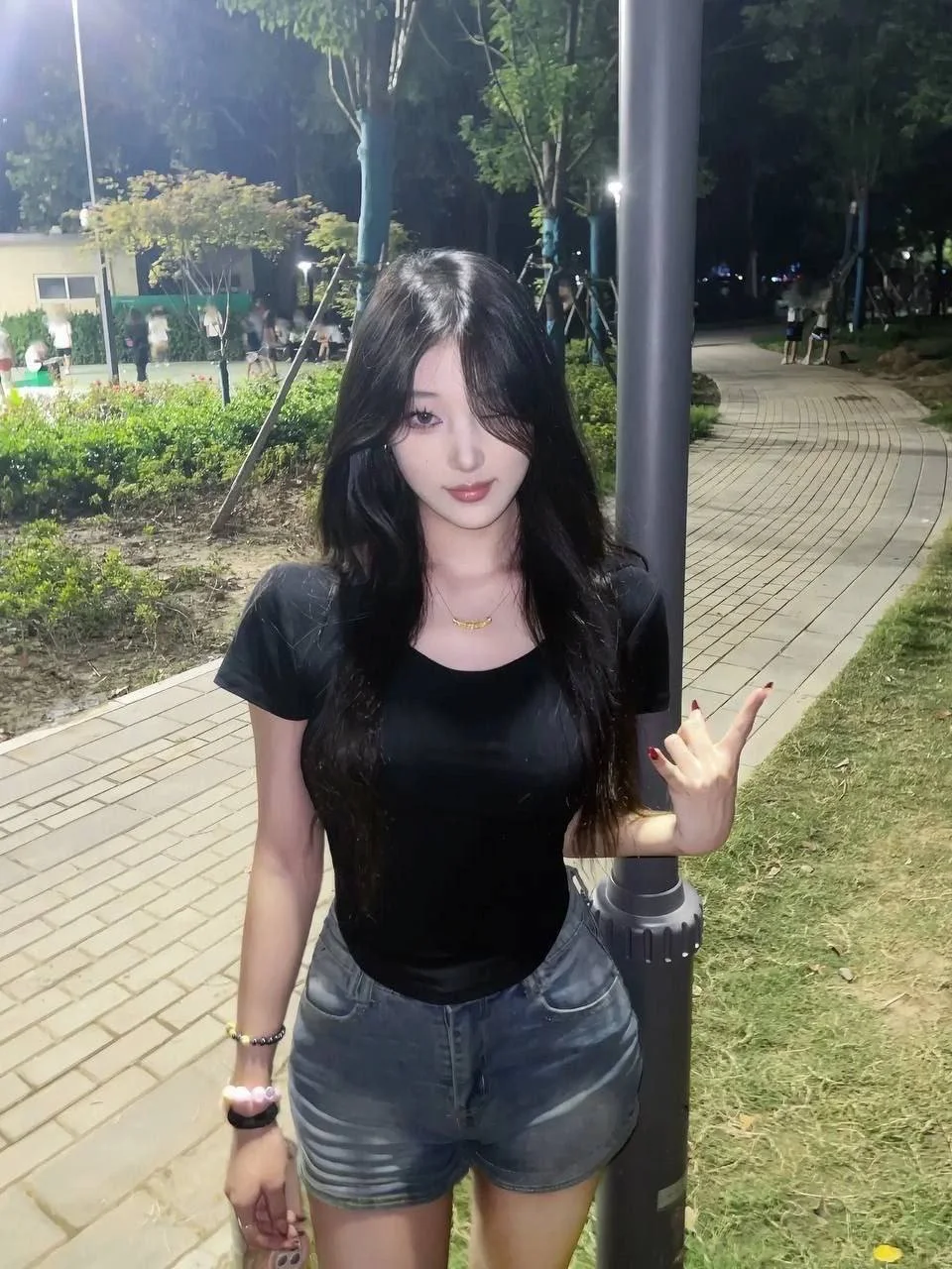 长发女孩靠着路灯比耶