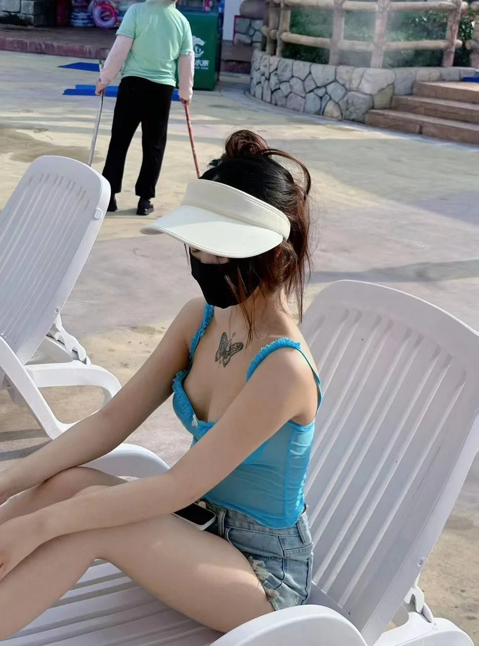 戴白遮阳帽女孩坐在泳池边椅子上